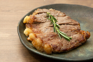 delicious roast beef, on a black plate and wooden surface, with a sprig of thyme on top