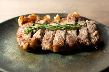 delicious roast beef, on a black plate and wooden surface, with a sprig of thyme on top. horizontal shot