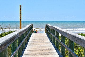Obraz premium Wooden board walkway over the dunes to the beach in Cocoa Beach near Cape Canaveral, Florida