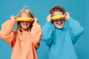 funny, cute children, a boy and a girl stand on a blue background in bright clothes and holding...