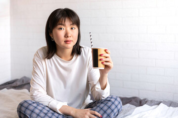 Asian teen girl on a white background holding paper coffee cup enjoying morning. Eco friendly