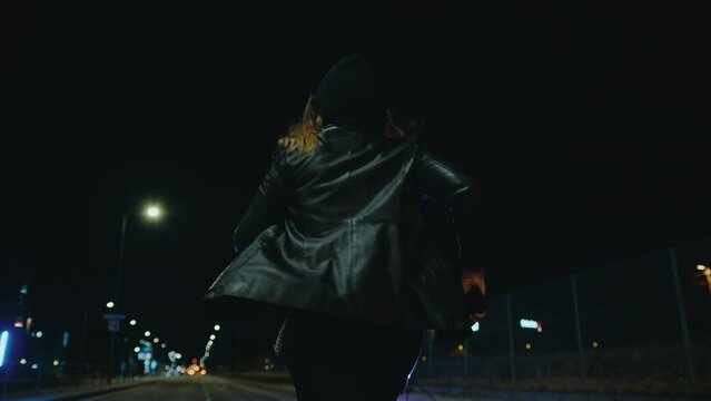 Hooded woman chased down street at night, slow motion
