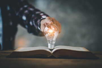 light bulb, Hand holding illuminated light bulb, innovation inspiration concept, Book or textbook...