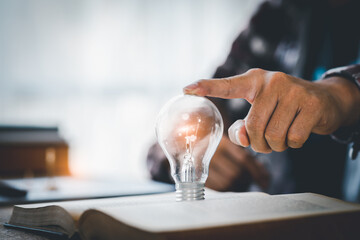 light bulb, Hand holding illuminated light bulb, innovation inspiration concept, Book or textbook with brainstorming glowing light bulb.