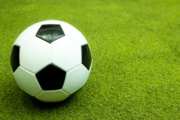 Fototapeta na wymiar Black and white football ball on the green artificial grass field for sport background.