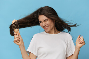 beautiful, middle-aged brunette combing her long beautiful hair with a wooden comb and rejoicing...