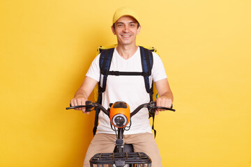 Food delivery. Portrait of smiling positive courier guy riding bike with backpack bag delivering...