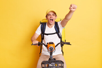 Portrait of positive happy optimistic deliveryman on bicycle wearing white T-shirt and cap isolated...