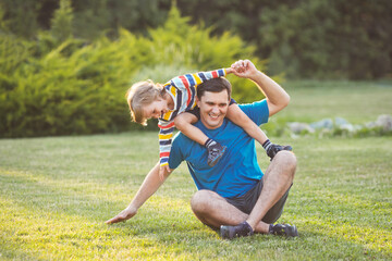 Family fun. Happy little son with dad playing and laughing together in backyard on lawn