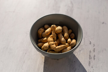 Maní tostado en un bol sobre un fondo de madera abstracto. Concepto de alimentos.