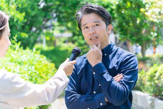 マイクインタビューを受けるミドル日本人男性