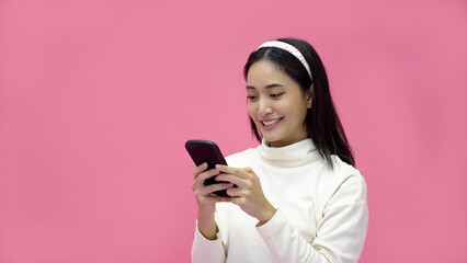 Asian woman smiling and using mobile phone with tablet and excited for online shopping on isolated pink background.
