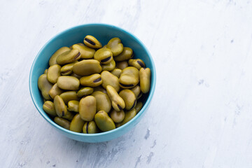 Habas hervidas servidas en un bowl con fondo blanco de madera.. Concepto de alimentos.