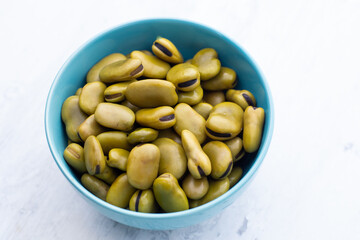 Habas hervidas servidas en un plato en un fondo azul abstracto. Concepto de alimentos.