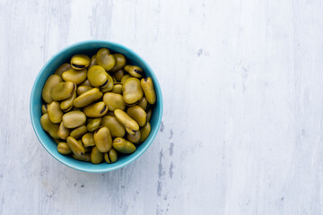 Habas hervidas servidas en un bowl con fondo blanco de madera.. Concepto de alimentos.