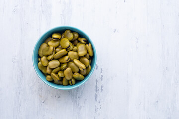 Habas hervidas servidas en un bowl con fondo blanco de madera.. Concepto de alimentos.