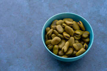 Habas hervidas servidas en un bowl con un fondo azul abstracto. Concepto de alimentos.