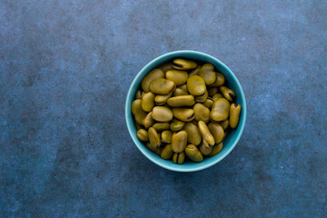Habas hervidas servidas en un bowl con un fondo azul abstracto. Concepto de alimentos.