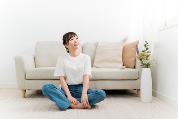 家のカーペットでリラックスする日本人女性（あぐら）
