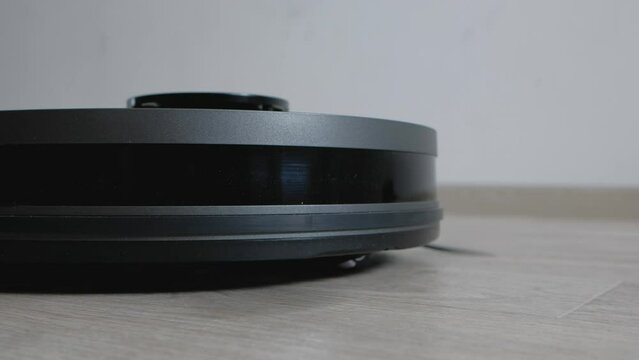 Robot vacuum cleaner vacuuming the floor in living room. Smart home with automated devices that simplify life. A smart vacuum cleaner cleans the floor. 
