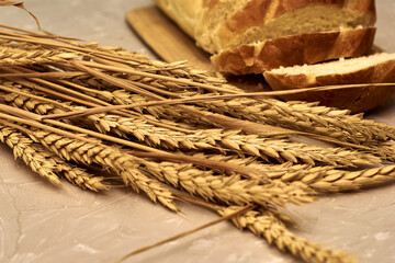 sliced loaf of bread on a cutting board and ears of wheat