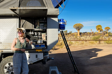 Woman tourist on safari travel vacation in Africa, young girl near camping car with tent and...