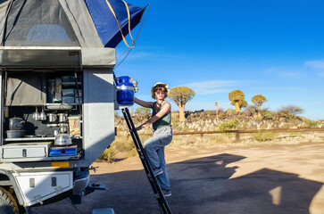 Woman tourist on safari travel vacation in Africa, young girl near camping car with tent and...
