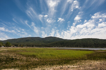 Meadow and mountains landscape with clouds coming towards you