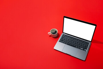 Coffee and laptop on red background, space for text