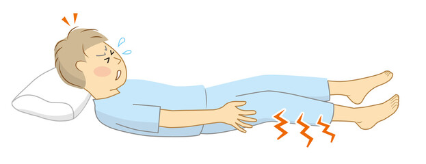 就寝中に足がつって目が覚めて、激痛に苦しんでいる男性
