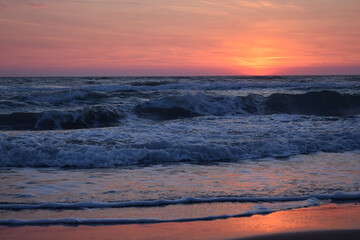Obraz premium A beautiful sunset on the beach in the turbulent ocean