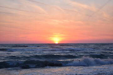 Fototapeta na wymiar A beautiful sunset on the beach in the turbulent ocean