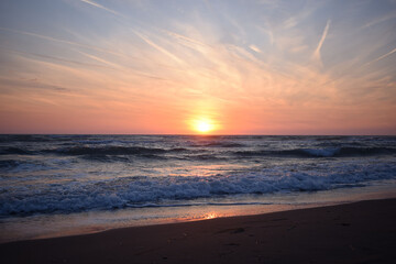Fototapeta na wymiar A beautiful sunset on the beach in the turbulent ocean