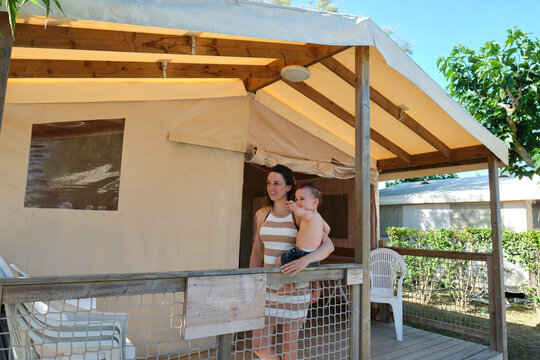 happy mother and toddler, enjoying a sunny day in a wooden and fabric cabin inside a campsite