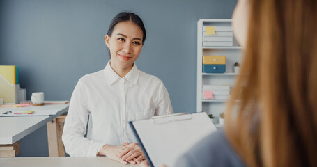 Obraz na płótnie Canvas Young Asia businesswomen applicant pass job interview for enterprise company position or during corporate business meeting sitting on office desk at workplace. Hire candidate at job interview concept.