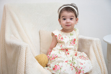 A girl is sitting against the background of a white wall dressed in twigs