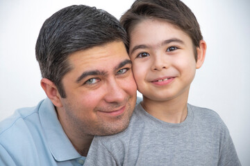 Obraz premium A man in a blue T-shirt is holding his son in his arms