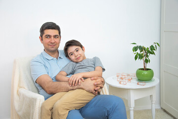 A man in a blue T-shirt is holding his son in his arms