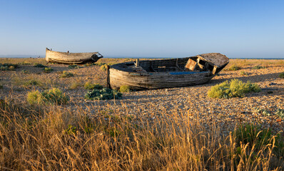 Old wrecked fishing boats on the shingle of Dungeness beach on the Kent coast south east England
