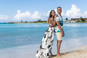 Young black couple standing on a white sand beach on a bright sunny day. Jamaican couple