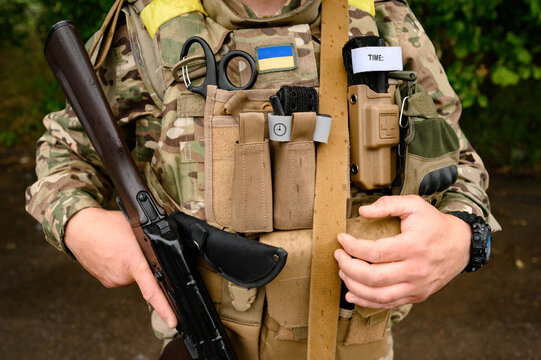 Military ammunition on a Ukrainian soldier with an assault rifle ak 74, bulletproof vest and medical turnstile. Ukrainian military and war. - Powered by Adobe