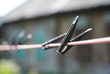 plastic black clothes pin on rope. Black Plastic Clothespins on a Clothesline for Drying Clothes - obrazy, fototapety, plakaty