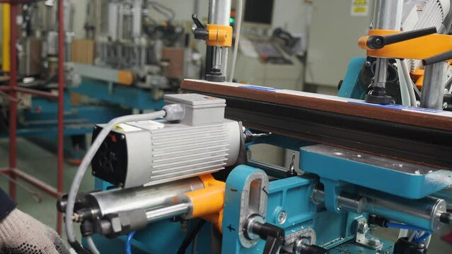 Plastic doors and windows manufacturing facility - machine processing PVC profile piece in factory production.