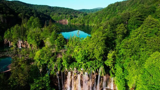 Set of waterfalls flowing from big dark water lake surrounded by green forest in Croatia