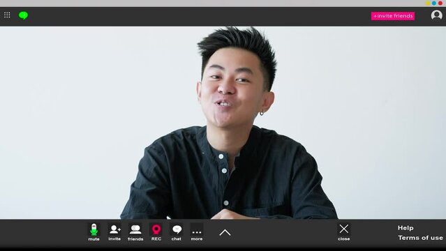 Online education. Greeting man. Screen mockup. Positive elegant guy sitting work desk showing hi gesture having webinar in light room interior.