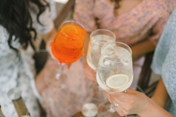 Several friends clinking glasses of limoncello tonic and aperol cocktails together in celebration.