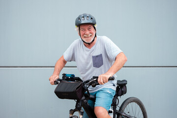 Happy attractive retired senior man with helmet enjoying sport activity with electric bicycle in...