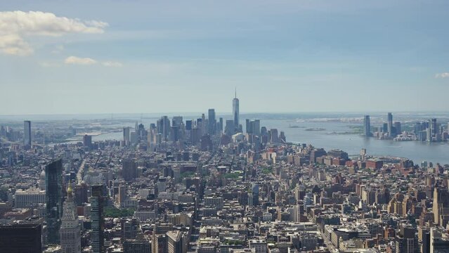 Panoramic view of Manhattan with the One World Trade Center and the Statue of Liberty in the distance on a sunny day, static shot.