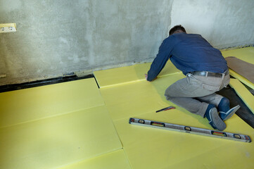 Installation of expanded polystyrene in the room for floor insulation, repair work alone, yellow...