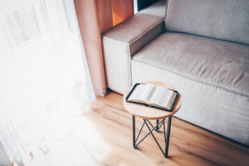 Open bible on table in living room, modern interior